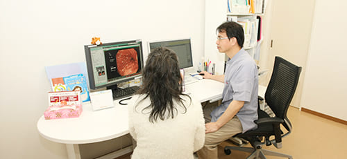 胃のレントゲン写真を見ながら患者に説明する菊地内科の院長